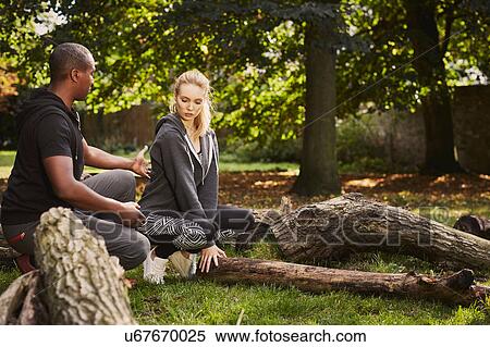 Stock Photography - Personal trainer showing young woman how to lift tree trunk in park. Fotosearch