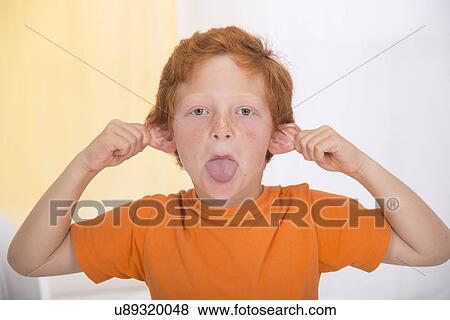 Stock Photo - Portrait of boy pulling a rude face. Fotosearch
