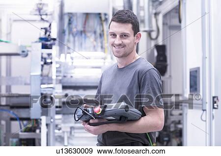 Portrait of engineer holding electronic control equipment in engineering plant View Large Photo Image Stock Photo - Portrait of engineer holding electronic control equipment in engineering plant. Fotosearch