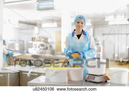 Stock Photograph - Portrait of female worker weighing curry powder in Asian food factory. Fotosearch