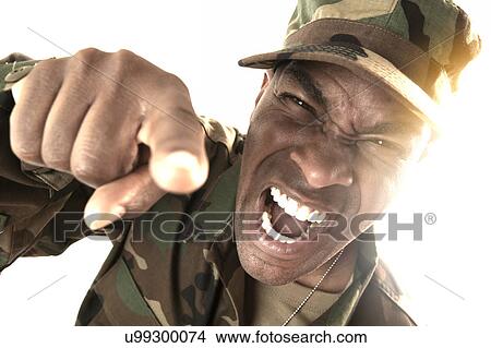 Picture - Portrait of man wearing camouflage clothing, screaming and pointing towards camera. Fotosearch