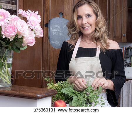 Portrait of mature woman picking fresh herbs plant in traditional Italian kitchen View Large Photo Image Stock Image - Portrait of mature woman picking fresh herbs plant in traditional Italian kitchen. Fotosearch