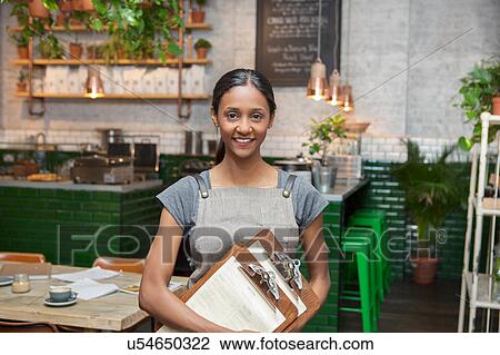 Stock Image - Portrait of mid adult female cafe owner in cafe. Fotosearch