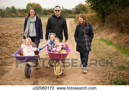 Portrait of parents pushing three girls in wheelbarrows along pumpkin field View Large Photo Image Stock Image - Portrait of parents pushing three girls in wheelbarrows along pumpkin field. Fotosearch