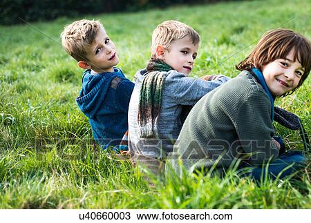 Portrait of three boys, sitting together in field, in autumn View Large Photo Image Stock Image - Portrait of three boys, sitting together in field, in autumn. Fotosearch