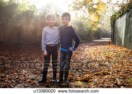 Stock Image - Portrait of twin boys, outdoors, surrounded by autumn leaves. Fotosearch
