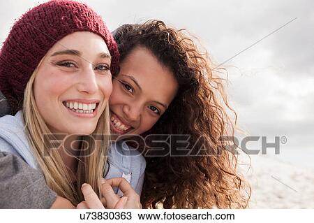 Stock Image - Portrait of two young female friends hugging at beach, Western Cape, South Africa. Fotosearch