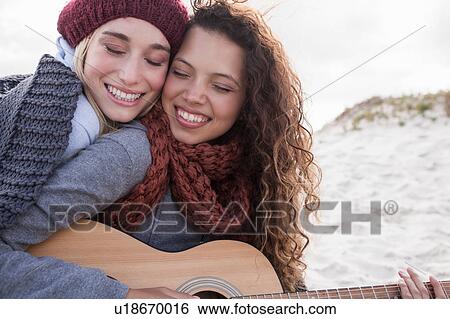Portrait of two young female friends playing guitar at beach, Western Cape, South Africa View Large Photo Image Stock Photograph - Portrait of two young female friends playing guitar at beach, Western Cape, South Africa. Fotosearch