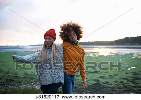 Stock Photo - Portrait of two young women by sea at sunset. Fotosearch