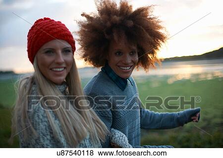 Stock Photo - Portrait of two young women by sea at sunset. Fotosearch