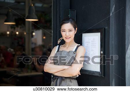 Stock Photo - Portrait of waitress in doorway of city sidewalk cafe. Fotosearch
