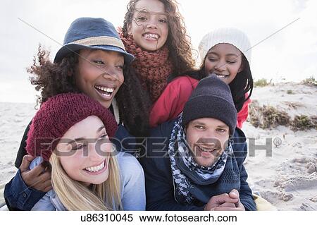 Stock Photography - Portrait of young adult friends lying on top of each other on beach, Western Cape, South Africa. Fotosearch