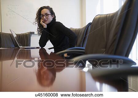 Portrait of young business woman sitting in conference room with laptop View Large Photo Image Stock Photo - Portrait of young business woman sitting in conference room with laptop. Fotosearch