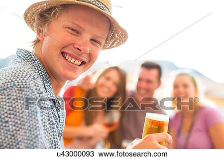 Stock Image - Portrait of young man with adult friends at waterfront restaurant, Majorca, Spain. Fotosearch