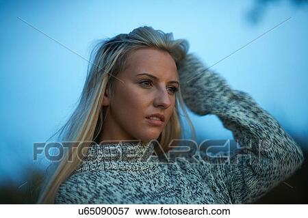 Portrait of young woman with hand in hair at dusk View Large Photo Image Stock Photo - Portrait of young woman with hand in hair at dusk. Fotosearch