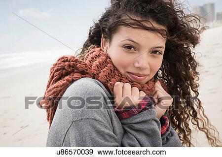 Stock Photo - Portrait of young woman wrapped in scarf on windy beach, Western Cape, South Africa. Fotosearch