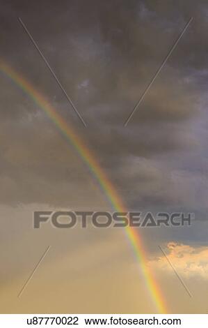 Stock Image - Rainbow against clouds in sunlight. Fotosearch