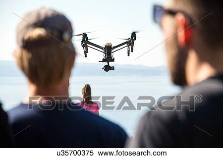 Rear view of man and woman looking at drone flying mid air over coast, Split, Dalmatia, Croatia View Large Photo Image Stock Photography - Rear view of man and woman looking at drone flying mid air over coast, Split, Dalmatia, Croatia. Fotosearch