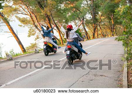 Stock Image - Rear view of two couples riding mopeds on rural road, Split, Dalmatia, Croatia. Fotosearch