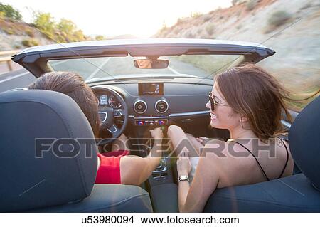 Rear view of two young women driving on rural road in convertible, Majorca, Spain View Large Photo Image Picture - Rear view of two young women driving on rural road in convertible, Majorca, Spain. Fotosearch