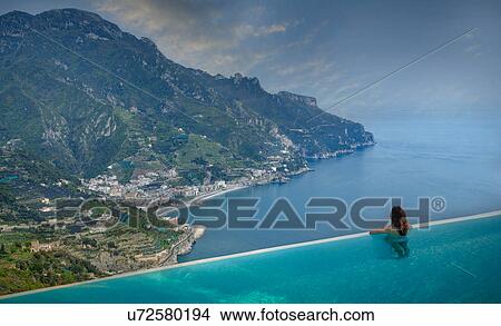 Rear view of woman looking out to coast from infinity pool, Ravello, Amalfi coast, Italy View Large Photo Image Picture - Rear view of woman looking out to coast from infinity pool, Ravello, Amalfi coast, Italy. Fotosearch