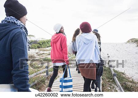 Rear view of young adult picnicking friends strolling along boardwalk at beach, Western Cape, South Africa View Large Photo Image Stock Image - Rear view of young adult picnicking friends strolling along boardwalk at beach, Western Cape, South Africa. Fotosearch