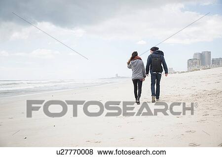 Stock Photo - Rear view of young couple strolling on beach, Western Cape, South Africa. Fotosearch