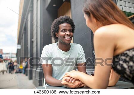 Stock Photograph - Romantic couple holding hands at city sidewalk cafe. Fotosearch