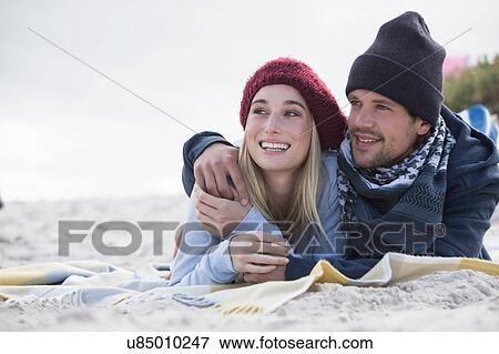 Stock Photo - Romantic young couple lying on picnic blanket at beach, Western Cape, South Africa. Fotosearch