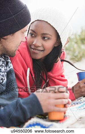 Stock Photograph - Romantic young couple picnicking on beach, Western Cape, South Africa. Fotosearch