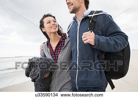 Picture - Romantic young couple strolling on windswept beach, Western Cape, South Africa. Fotosearch
