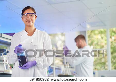Scientist holding bottle of liquid smiling at camera View Large Photo Image Stock Image - Scientist holding bottle of liquid smiling at camera. Fotosearch