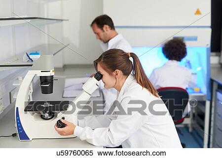 Stock Photography - Scientist in laboratory looking through microscope. Fotosearch