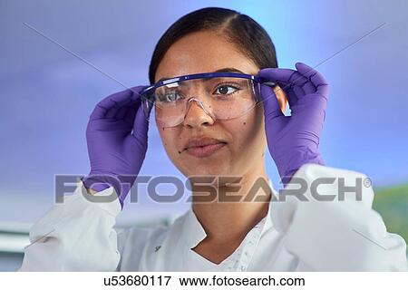 Stock Photo - Scientist putting on safety glasses. Fotosearch