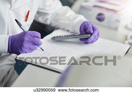 Scientist using calculator writing in notebook View Large Photo Image Stock Photo - Scientist using calculator writing in notebook. Fotosearch