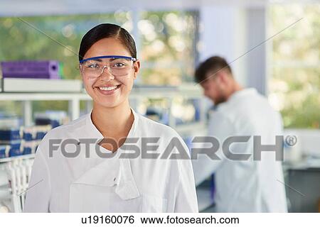 Stock Photograph - Scientist wearing safety glasses smiling at camera. Fotosearch