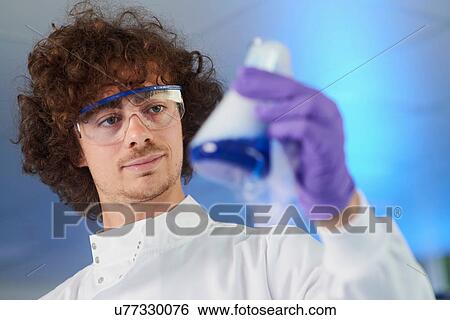 Scientist wearing safety glasses holding conical flask View Large Photo Image Stock Photograph - Scientist wearing safety glasses holding conical flask. Fotosearch