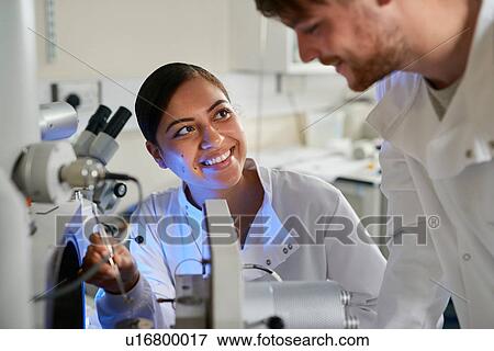 Stock Photo - Scientists in laboratory using scientific equipment smiling. Fotosearch