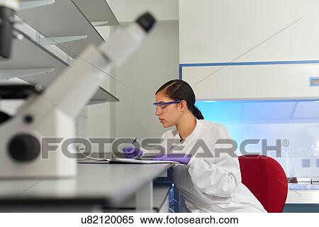 Stock Photography - Scientists in laboratory writing in notebook. Fotosearch