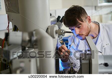 Scientists placing object on scientific equipment using tweezers View Large Photo Image Picture - Scientists placing object on scientific equipment using tweezers. Fotosearch