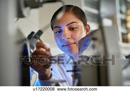 Stock Photo - Scientists placing object on scientific equipment using tweezers. Fotosearch