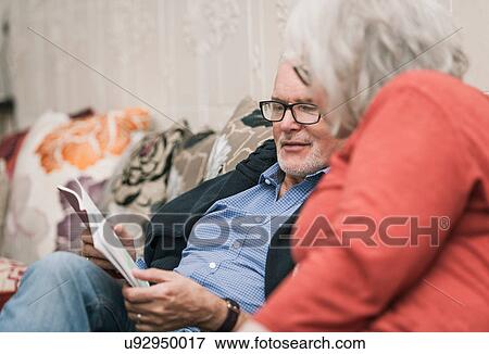 Stock Photo - Senior couple reading book on couch. Fotosearch