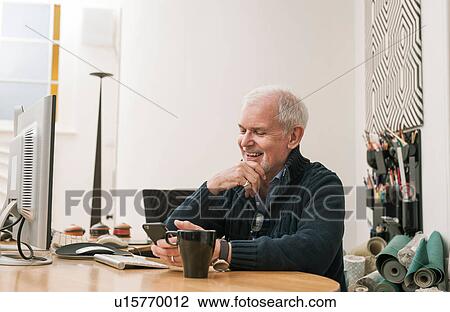 Senior man smiling, using mobile phone at work desk View Large Photo Image Stock Image - Senior man smiling, using mobile phone at work desk. Fotosearch