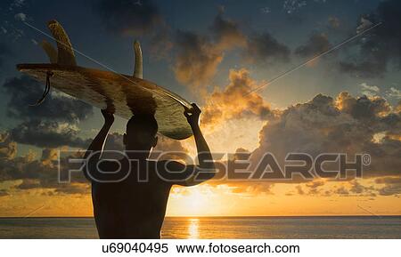 Silhouetted rear view of male surfer carrying surfboard on head watching sunset over sea, Rio De Janeiro, Brazil View Large Photo Image Stock Photography - Silhouetted rear view of male surfer carrying surfboard on head watching sunset over sea, Rio De Janeiro, Brazil. Fotosearch