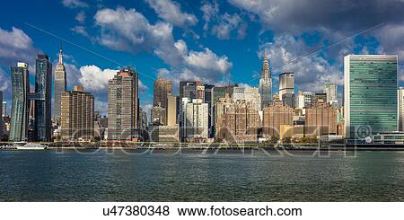 Stock Photo - Skyline of Midtown Manhattan seen from the East River showing the Chrysler Building and the United Nations building, New York. Fotosearch