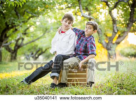 Stock Image - Smiling brothers embracing in cherry orchard. Fotosearch