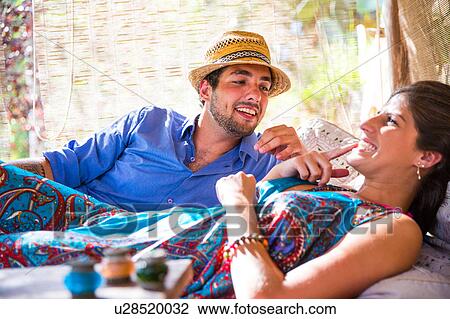 Stock Image - Smiling couple lying down taking chatting. Fotosearch