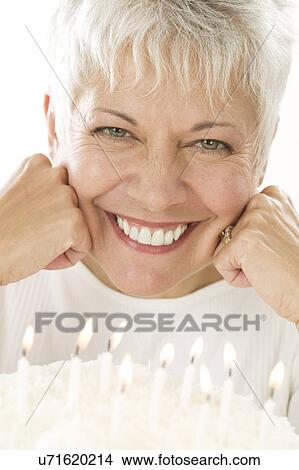 Picture - Smiling mature woman with birthday cake. Fotosearch