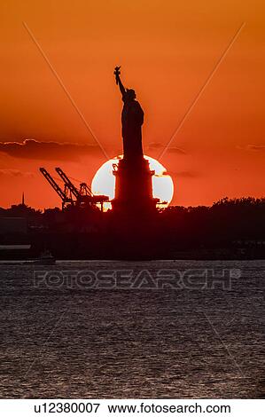 Stock Photo - Statue of Liberty sunset. NYC harbor, Manhattan. Fotosearch