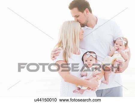 Studio shot of happy family with two baby girls (2-5 months) on white background View Large Photo Image Stock Image - Studio shot of happy family with two baby girls (2-5 months) on white background. Fotosearch